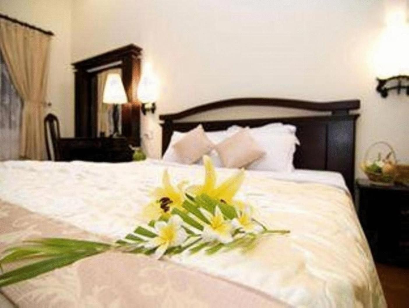 A hotel room with a bed, a nightstand, a lamp, and a mirror.