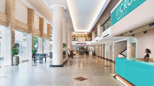 Un hall d’entrée spacieux avec de hauts plafonds, un comptoir d’accueil et un piano.