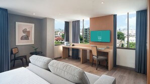 Une chambre d’hôtel moderne dotée d’un grand lit, d’un bureau, d’une chaise, d’une télévision et offrant une vue sur la ville.