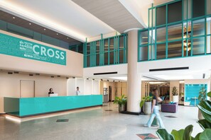 Un moderno vestíbulo de hotel con mostrador de recepción, ventanas amplias y plantas de interior.