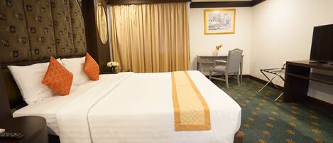 Een hotelkamer met een groot bed, een bureau, een stoel en een televisie.