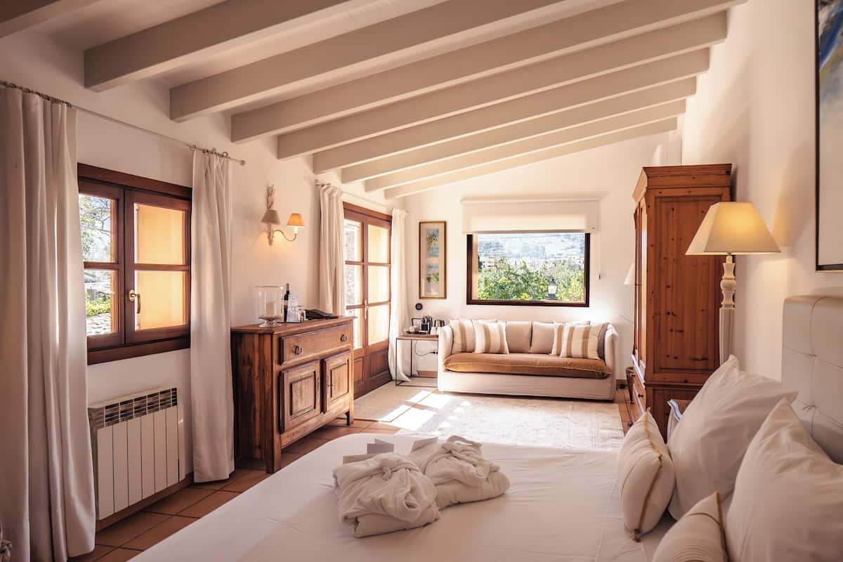 A room with a bed, a sofa, a wooden cabinet, and a window with a view.