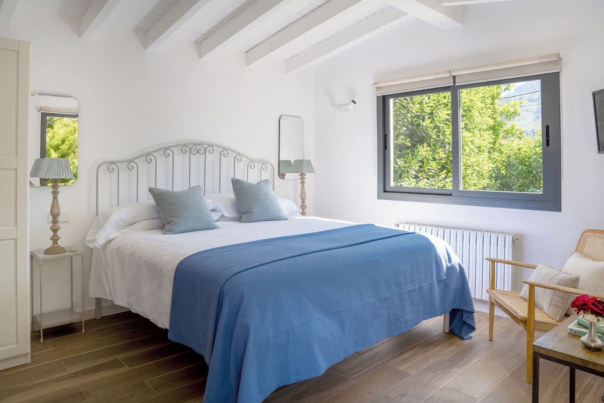 A bedroom with a bed, a window, a chair, and a table.
