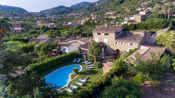 Une villa avec piscine, entourée d’une végétation luxuriante et de collines.