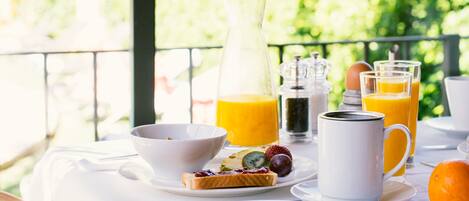 A breakfast table with plates of food, a pitcher of orange juice, and a glass of orange juice.