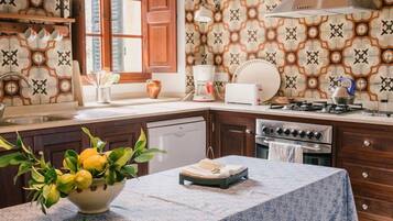A kitchen with a patterned backsplash, a stove, a sink, and a bowl of lemons on the counter.
