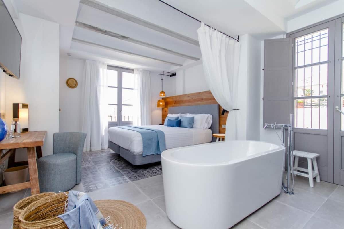 Un dormitorio moderno con una cama grande, una bañera y un cabecero de madera.