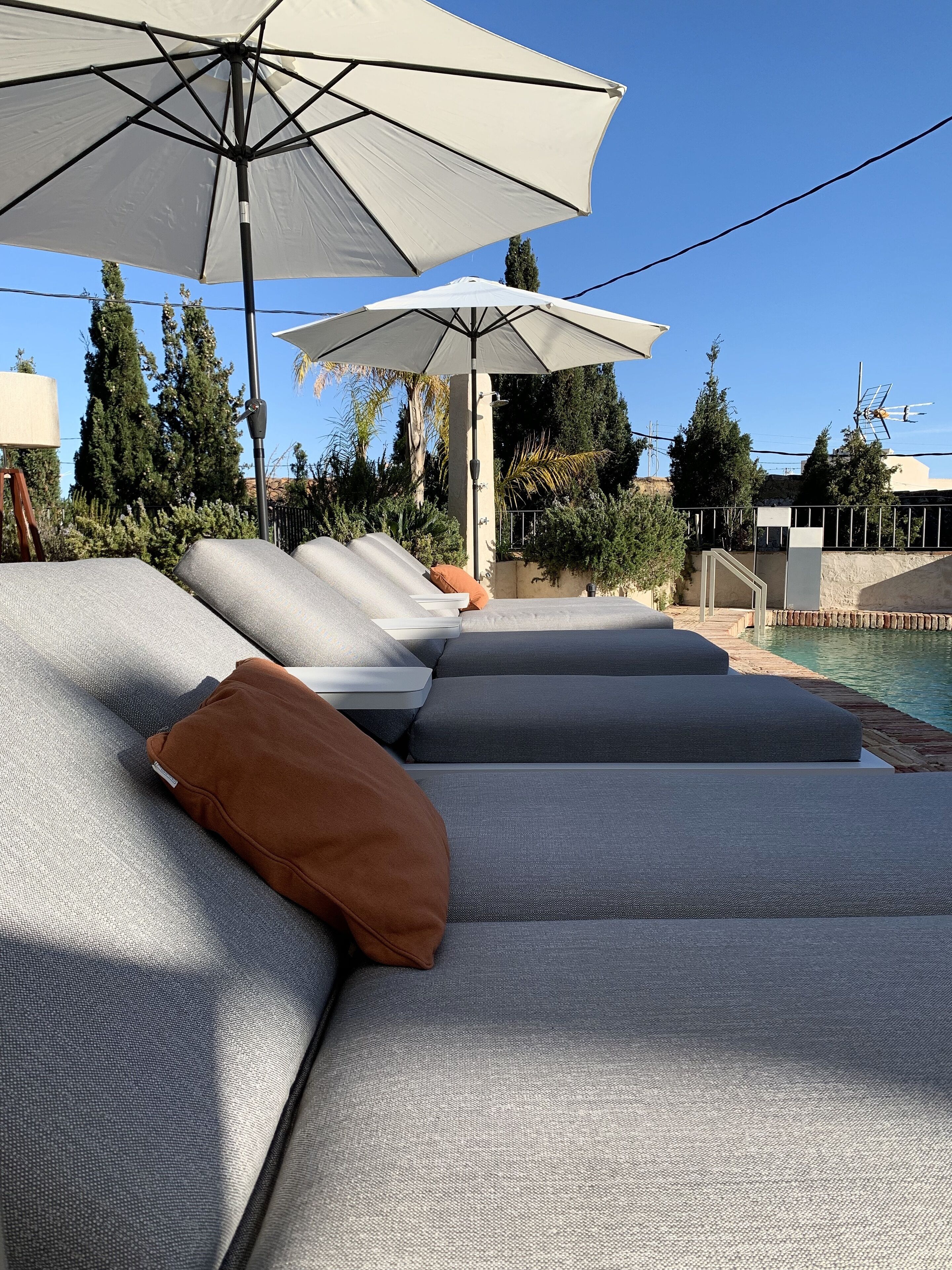 A poolside area with multiple lounge chairs and umbrellas.