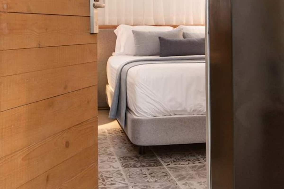 Una habitación de hotel moderna con una pared de madera, una cama con ropa blanca y el número de habitación 11 visible.