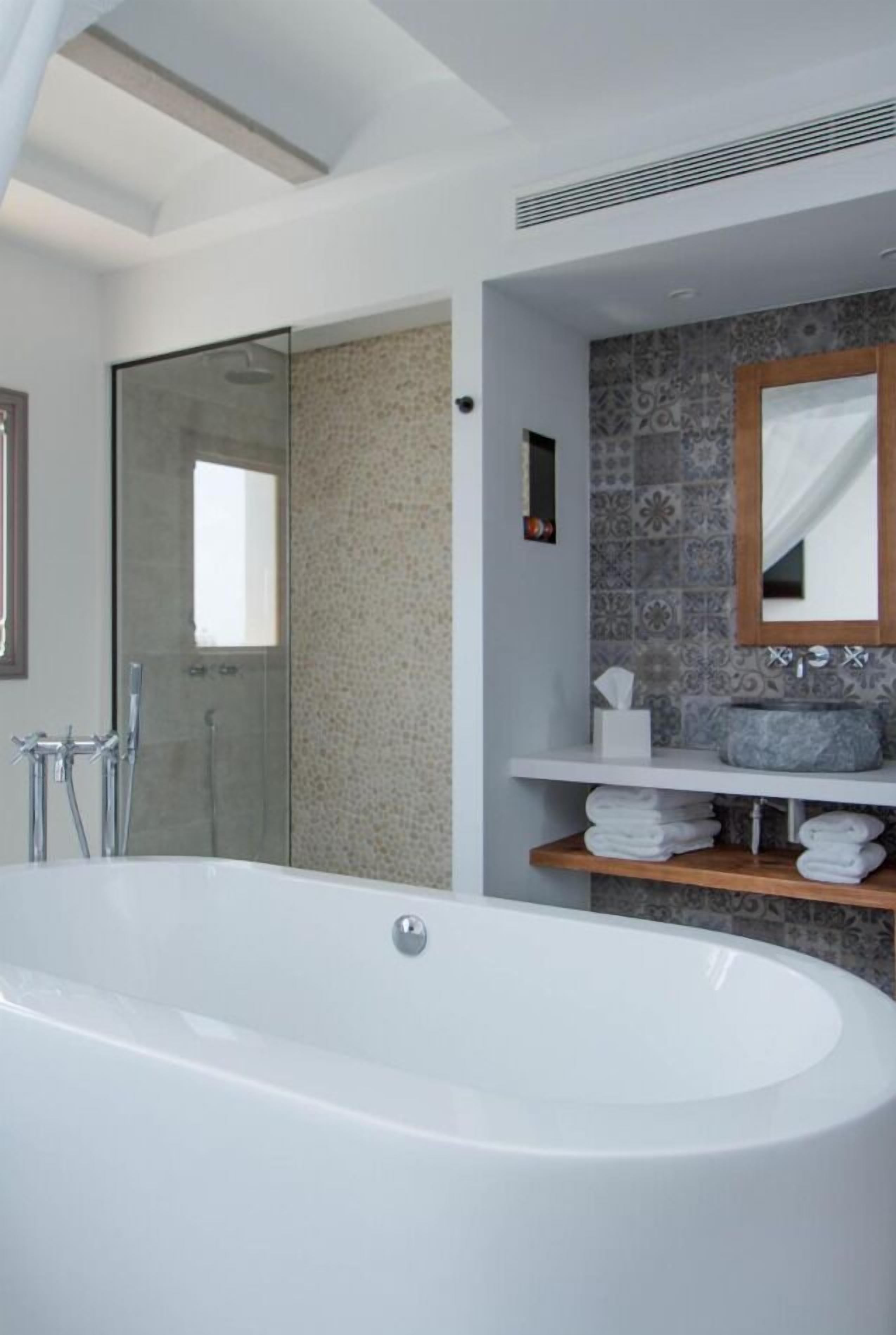 A modern bathroom with a freestanding bathtub, a glass shower enclosure, and a vanity with a tiled backsplash.