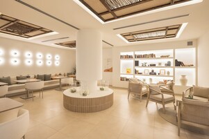 A modern interior with a central round table, seating arrangements, and a bookshelf with books and decorative items.