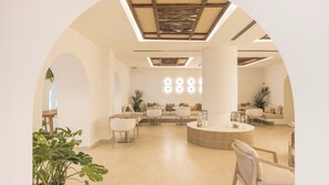 Un'ampia hall con zona salotto centrale, soffitto alto con finestra a lucernario e design moderno.