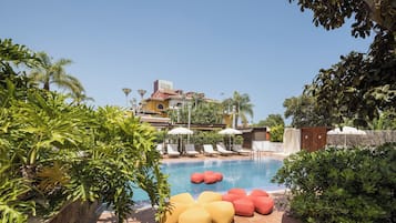 A pool area with lounge chairs, a sign reading 'Cook House,' and lush greenery.