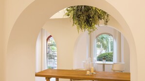 Zona pranzo con tavolo in legno, sedie e piante pensili.