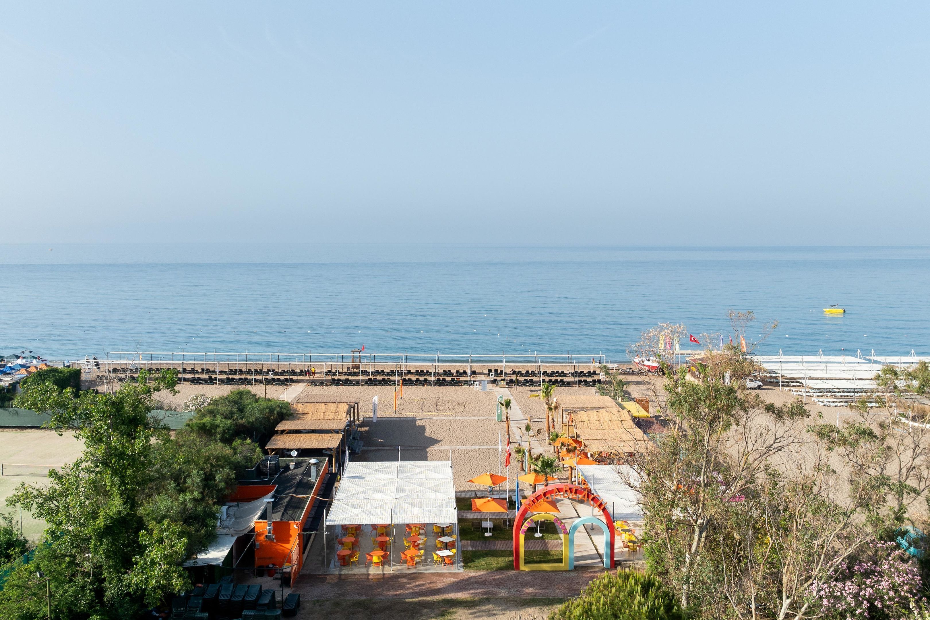 A beachside area with a covered seating area, a lifeguard tower, and a pier extending into the water.
