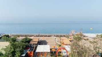 A beachside area with a covered seating area, a lifeguard tower, and a pier extending into the water.