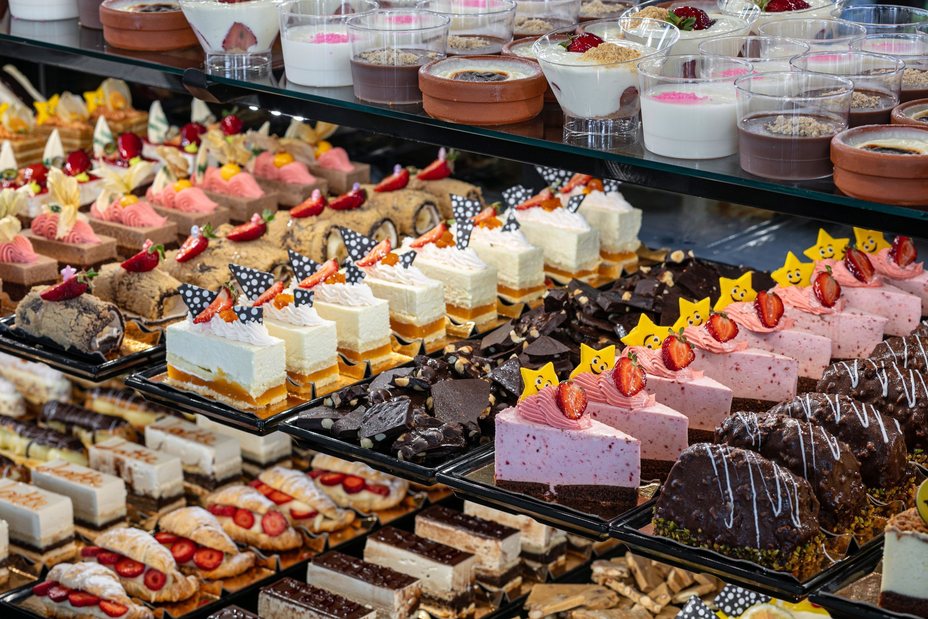 Diversos postres exhibidos en bandejas en una panadería o pastelería.