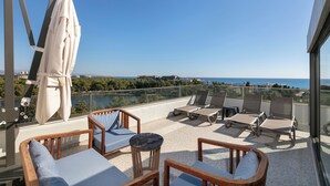 Un balcon doté de mobilier en bois, d’une table et offrant une vue sur la mer.