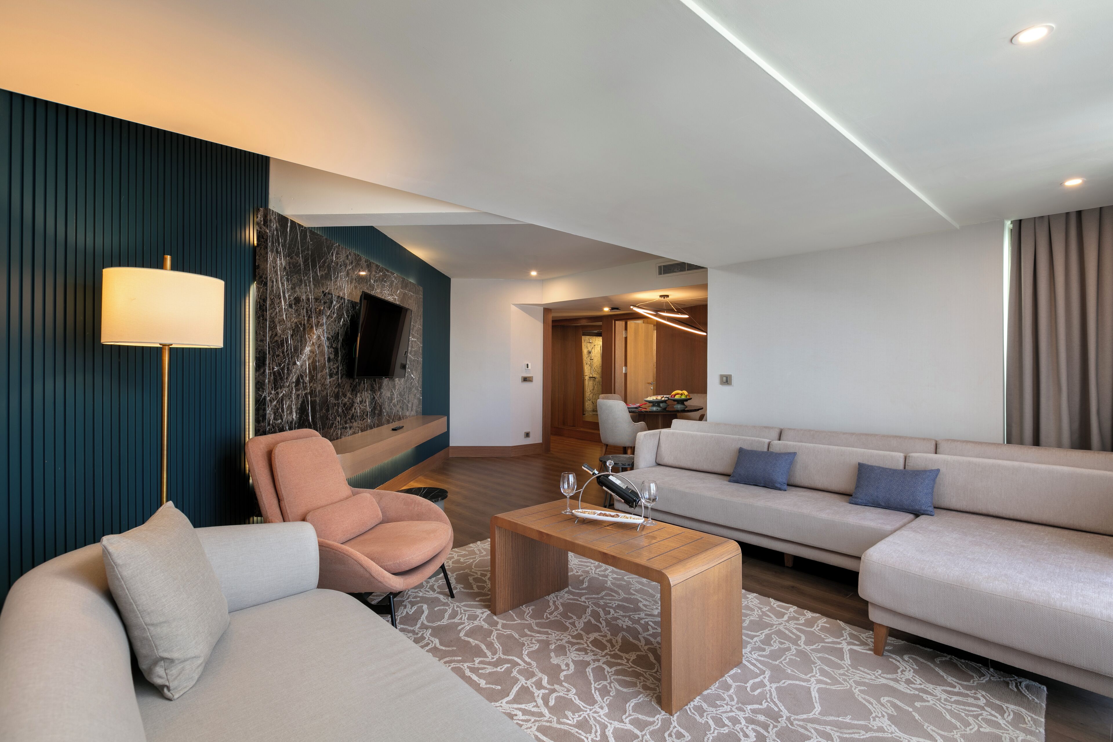 Una sala de estar moderna con sofá, sillón, mesa de centro y televisor montado en la pared.
