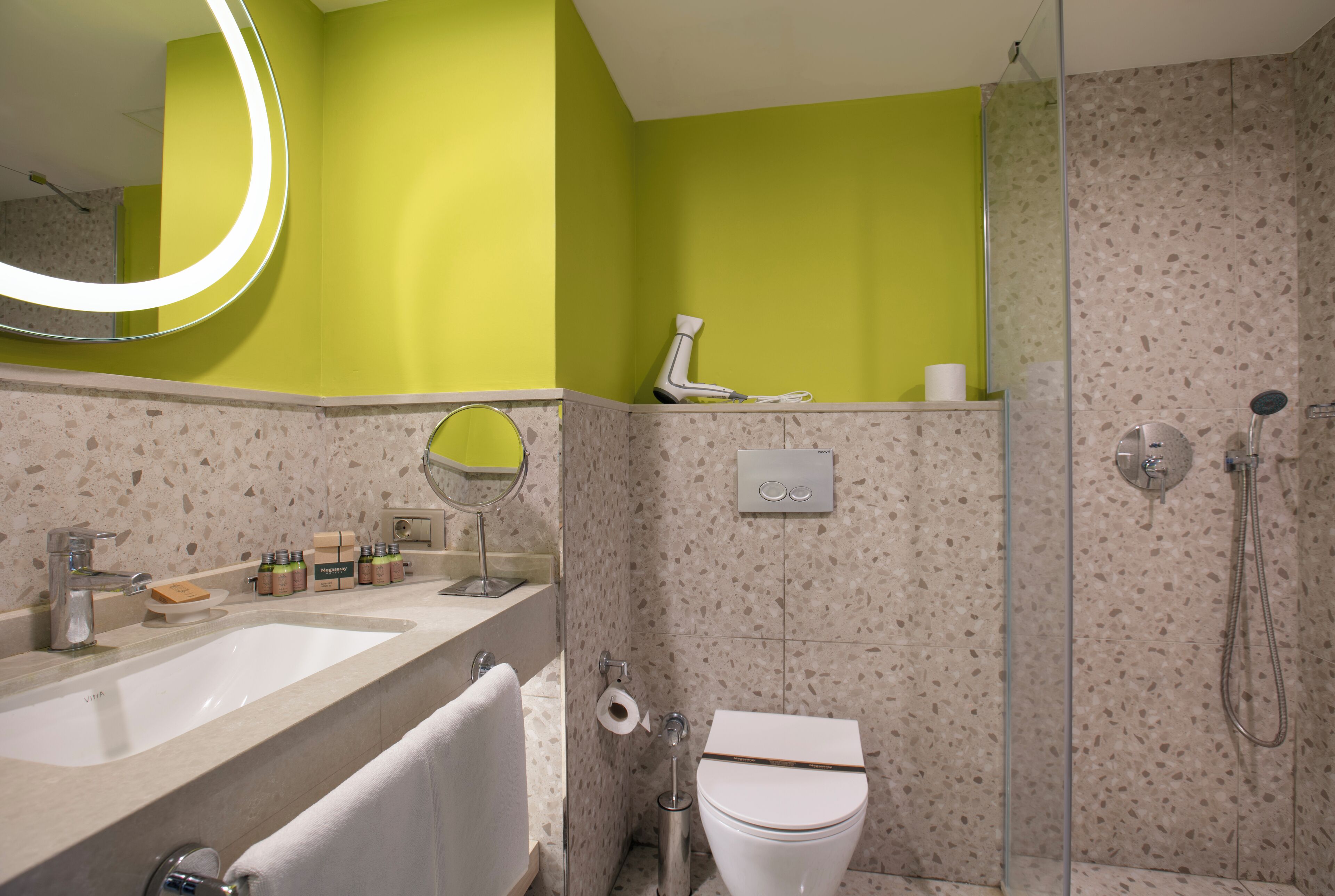 A bathroom with a sink, mirror, toilet, and shower.
