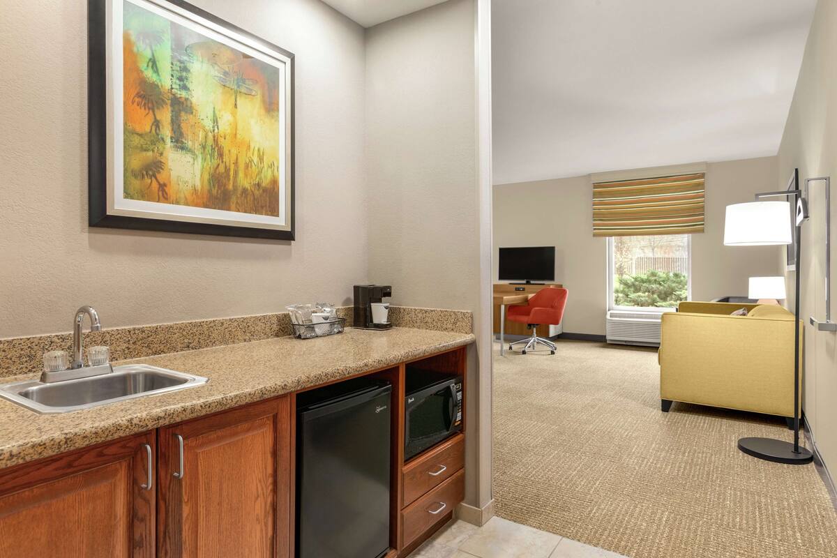 A hotel room with a kitchen area, a dining area, and a living space.