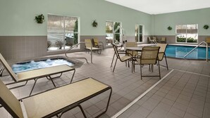 Zona de piscina con sillones de descanso y una bañera de hidromasaje.