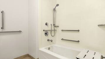 A modern bathroom with a bathtub, shower, and grab bars.