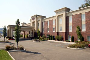 A hotel with a brick facade, multiple windows, and a parking lot with marked spaces.