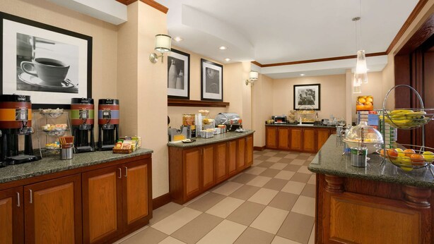 Zona de desayuno de hotel con un sistema de buffet, que incluye cafeteras, fruta y bollería.