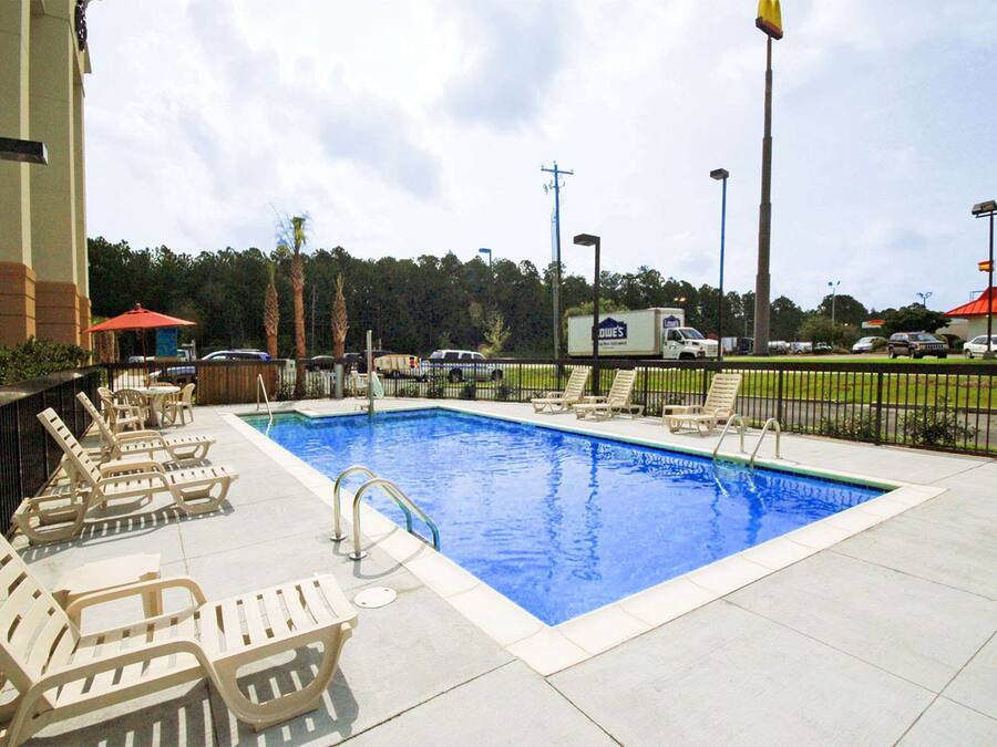 A swimming pool with lounge chairs and a flagpole.