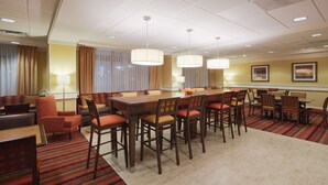 A hotel dining area with a long table, multiple chairs, and a patterned carpet. - Hampton Inn Moss Point Pascagoula (Moss Point)