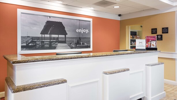 A reception desk with a large poster of a beach scene and the word "enjoy." - Hampton Inn Moss Point Pascagoula (Moss Point)