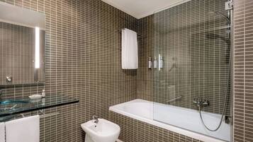 Un baño moderno con cabina de ducha de vidrio, bañera blanca y bidé.