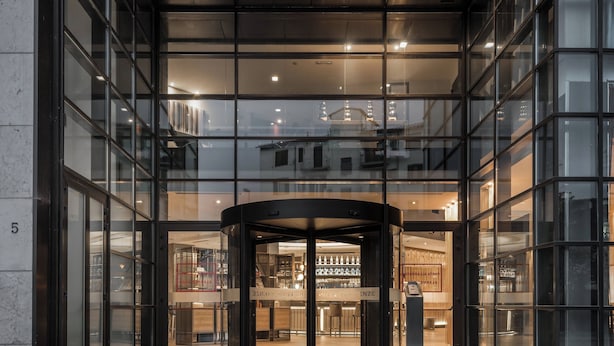A modern hotel entrance with a revolving door, large glass windows, and a visible bar area inside. - AC Hotel Firenze by Marriott (Florence)