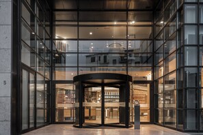 A modern hotel entrance with a revolving door, large glass windows, and a visible bar area inside. - AC Hotel Firenze by Marriott (Florence)