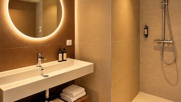 A modern bathroom with a round mirror, a white sink, and a shower area.