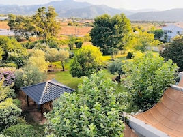 Un jardín con un pabellón, vistas al campo y un edificio con techo inclinado.