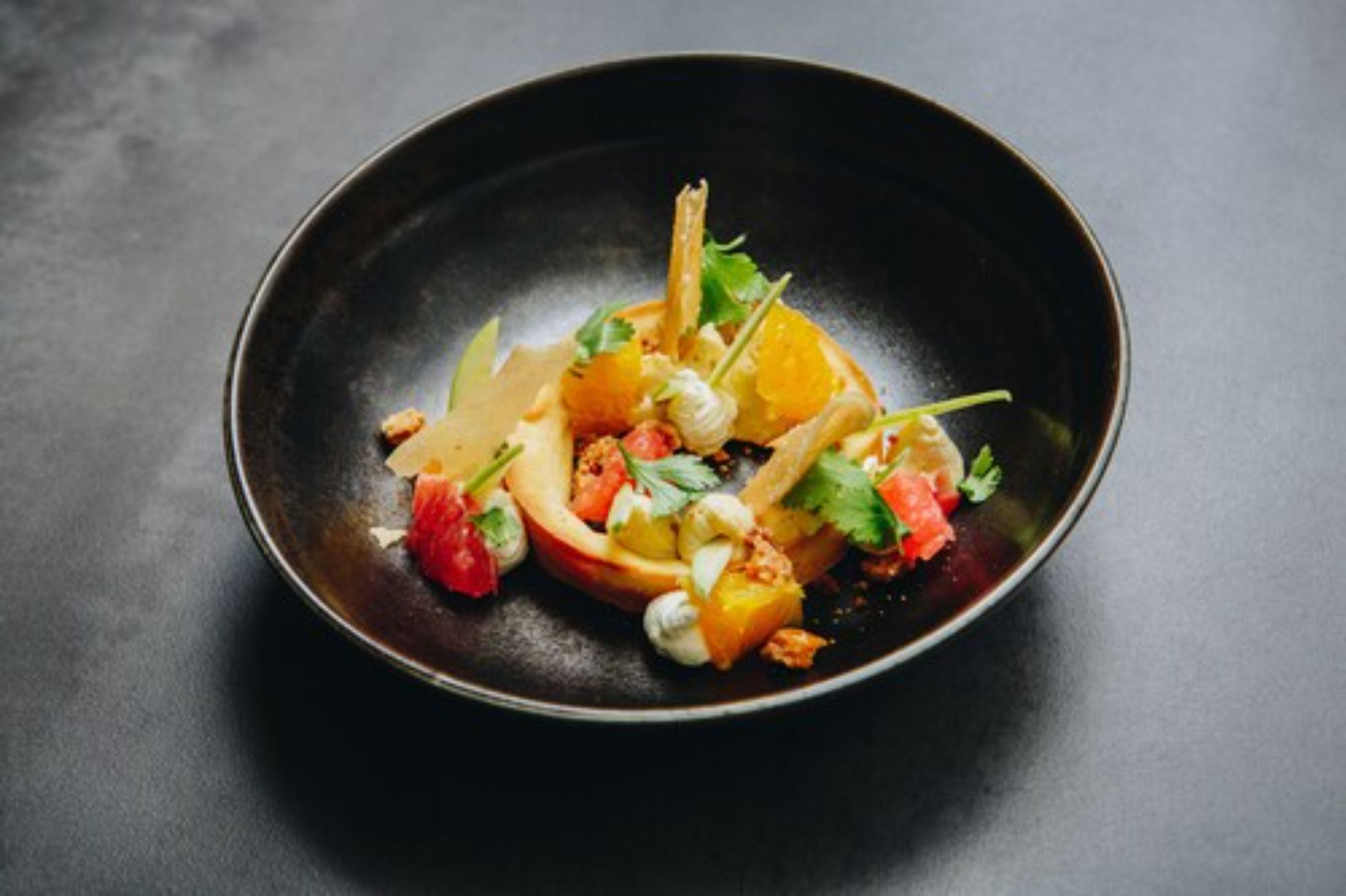 Un plato oscuro con diversas frutas y verduras.