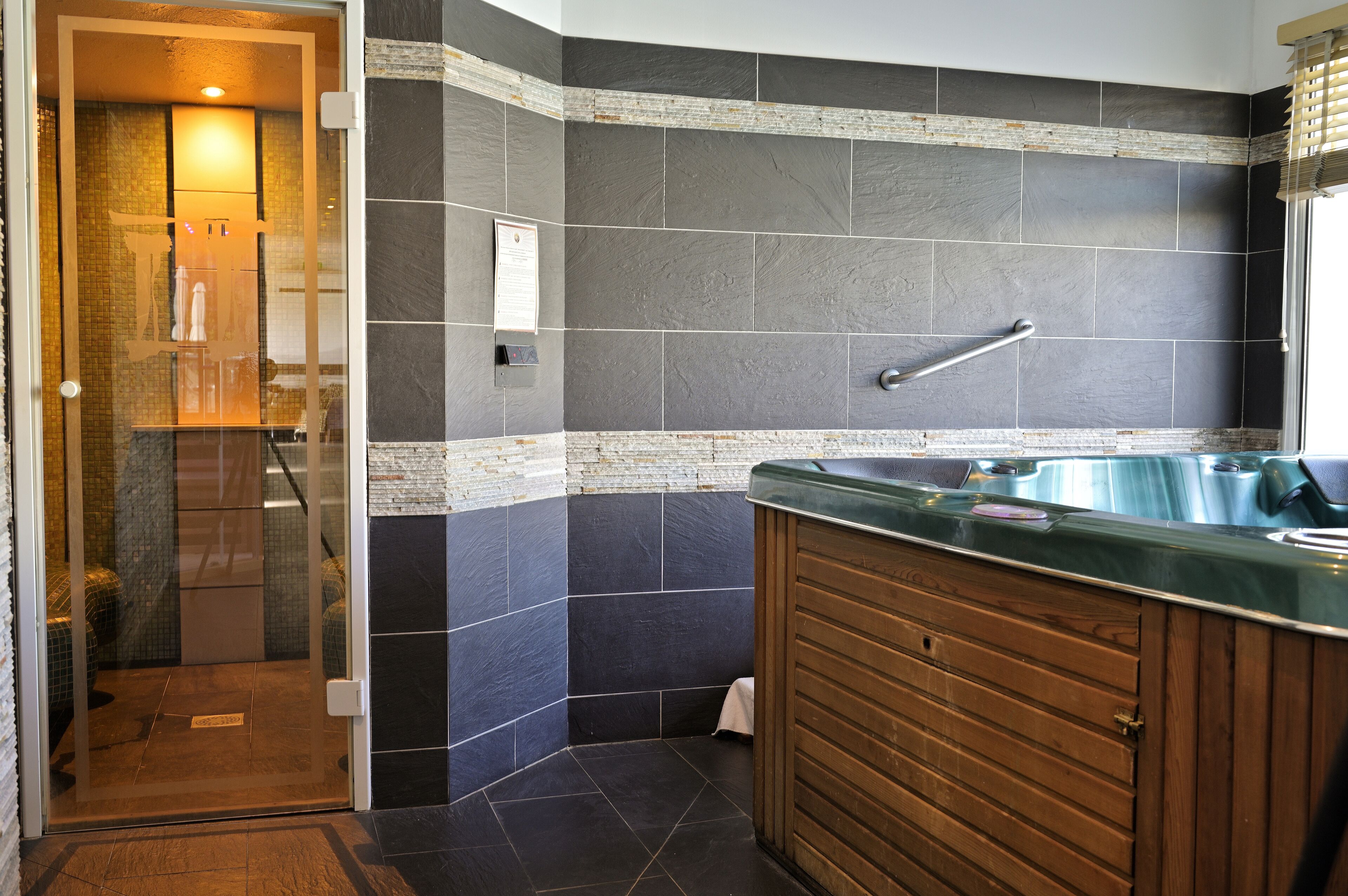 Un baño con cabina de ducha de vidrio, tocador de madera con encimera verde y una bañera grande.