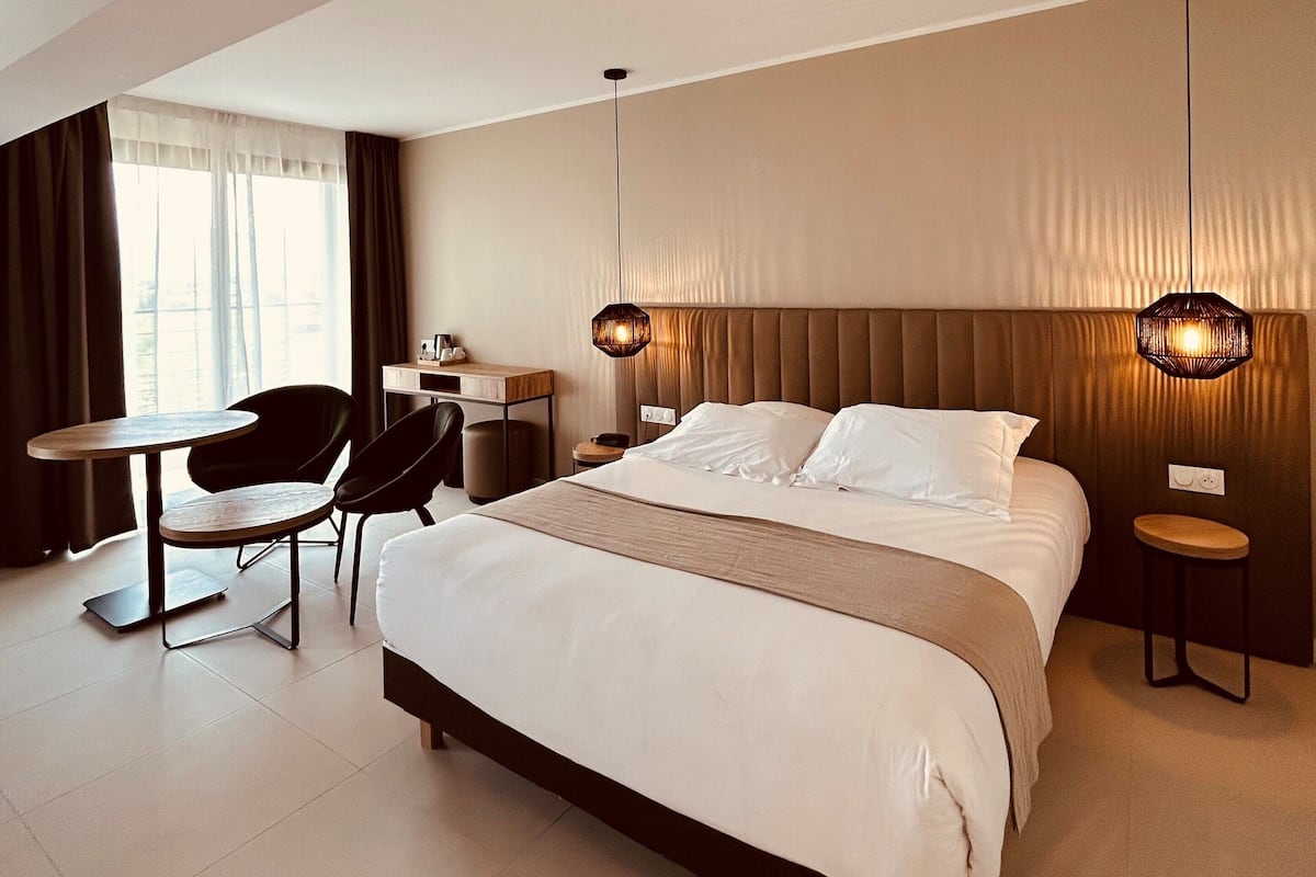 Une chambre d’hôtel moderne avec un grand lit, un bureau, une chaise et une petite table.