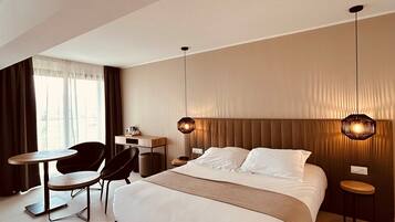Une chambre d’hôtel moderne avec un grand lit, un bureau, une chaise et une petite table.