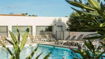 A pool area with lounge chairs and a building with large windows.