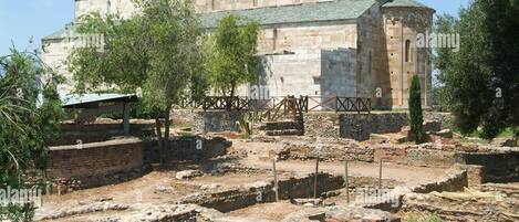 An ancient stone building with ruins in the foreground.