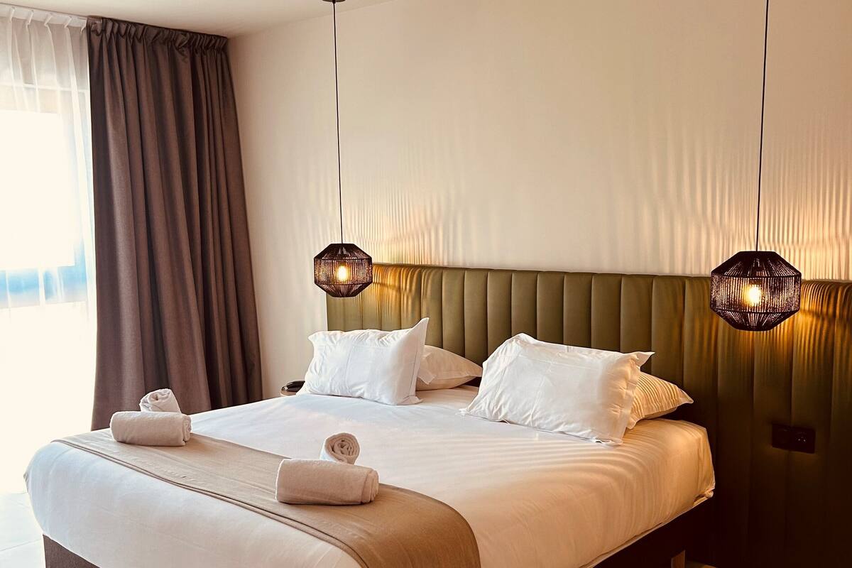 Une chambre d’hôtel moderne avec un grand lit, deux lampes de chevet et une vue sur l’extérieur.