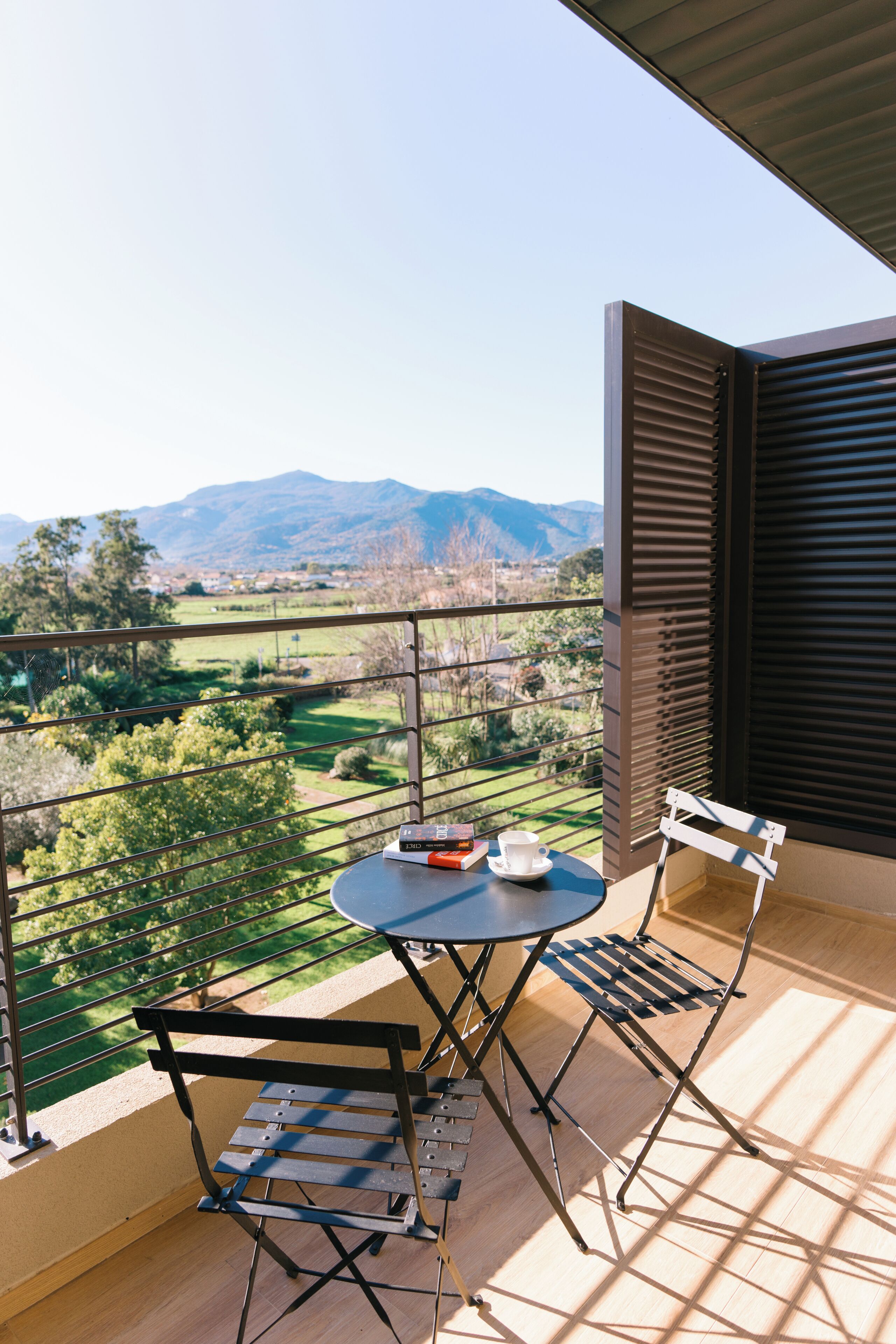 Een balkon met een tafel, stoelen, een boek en een kop.