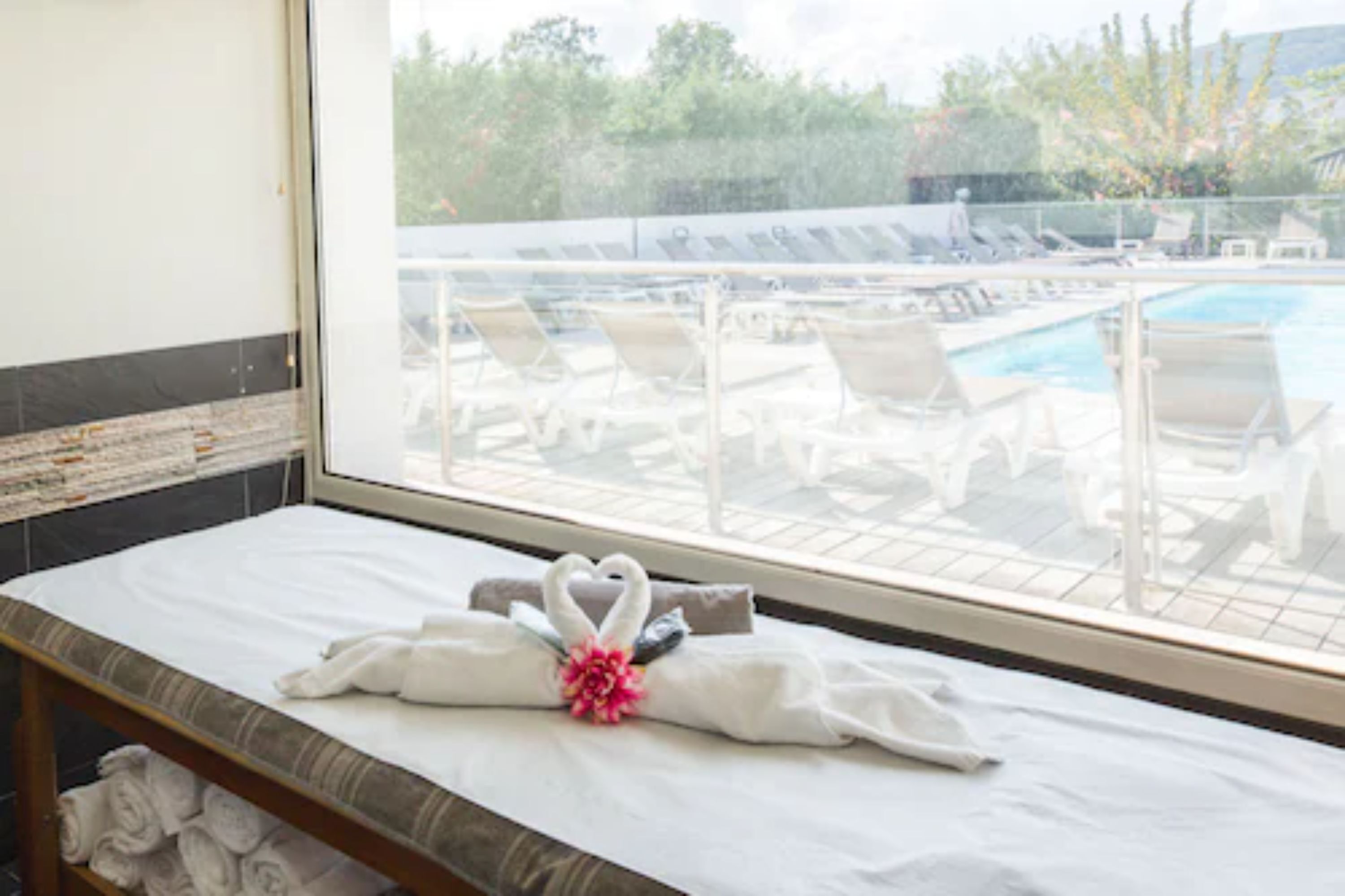 Une chambre d’hôtel avec vue sur une piscine et des chaises longues.