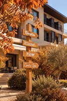 A wooden signpost with directional arrows pointing to amenities such as a reception, restaurants, a spa, and a pool.