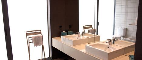 Une salle de bain moderne avec deux lavabos, un miroir et un porte-serviettes.