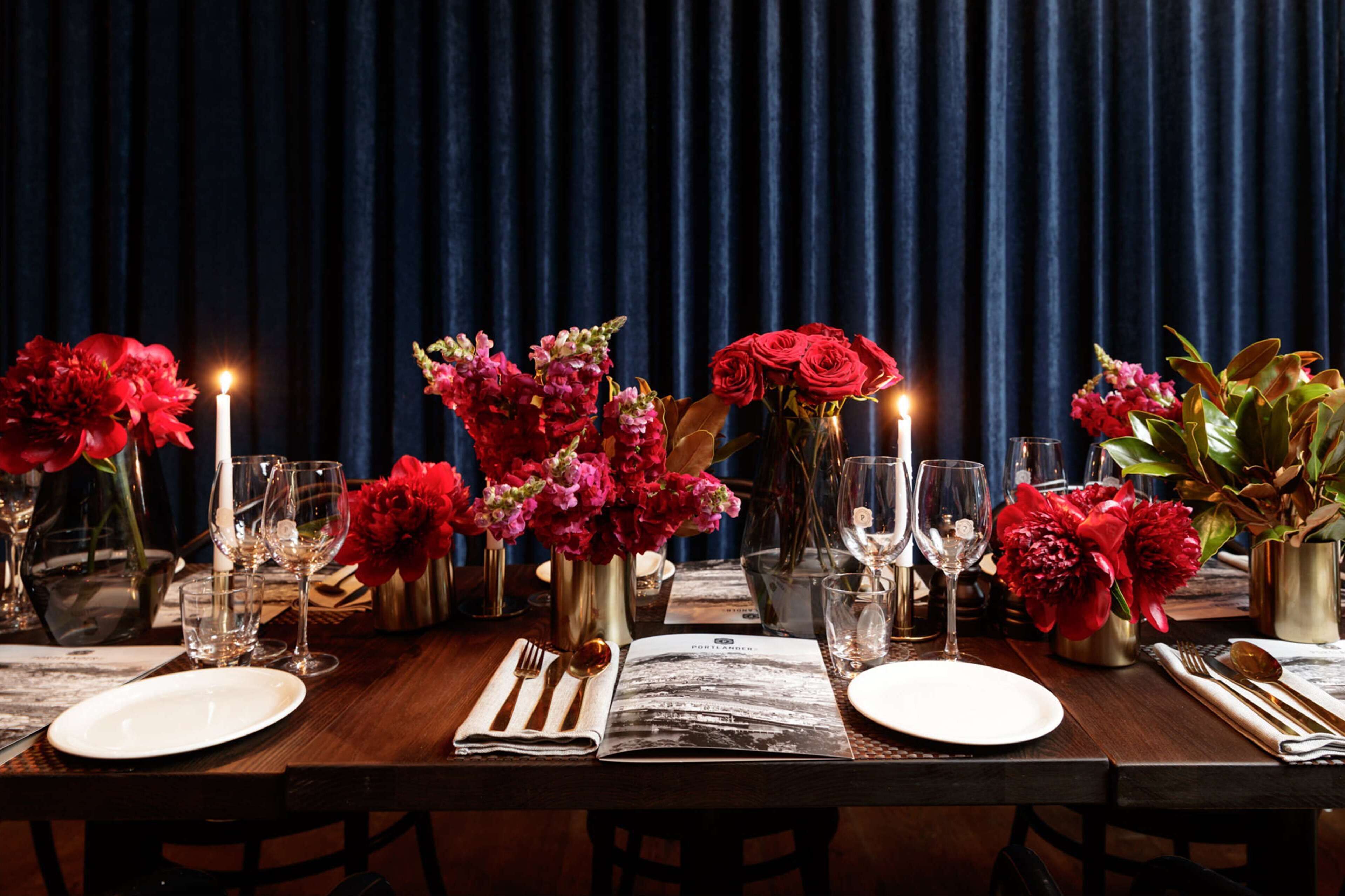 Una mesa lista para comer, adornada con centros de flores, velas y copas de vino.
