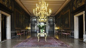 A grand lobby with a chandelier, ornate furniture, and a large floral arrangement. - Ca' Sagredo (Venice)